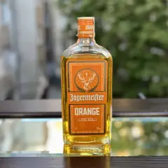 Butelka Jägermeister Orange na lustrzanym tle.