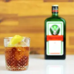 Szklanka z drinkiem i cytryną obok butelki Jägermeister. Ten jager alkohol to idealny dodatek do wieczoru.
