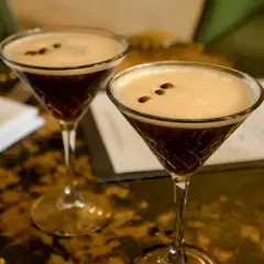Dwa kieliszki Espresso Martini z gęstą pianką i ziarnami kawy na wierzchu.