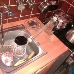 Zlew kuchenny z kranem, szklana rurka fermentacyjna, słoik z czarną cieczą i kawałki mięsa.