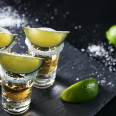 Trzy kieliszki tequili z solą i limonką, gotowe do degustacji. Oto jak pić tequilę, by poczuć jej smak.