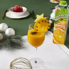 Pomarańczowy koktajl w kieliszku, ozdobiony plasterkiem pomarańczy z goździkami i gwiazdką anyżu.