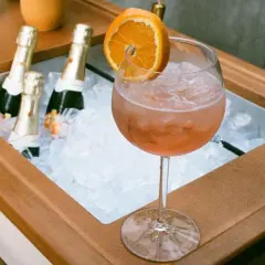 Orzeźwiający drink z pomarańczą i lodem, obok schłodzone butelki, idealne na aperitivo. Zastanawiasz się, jakie prosecco do Aperola?