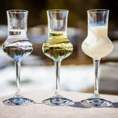 Trzy kieliszki z różnymi alkoholami, w tym jeden z mlecznym likierem.