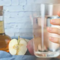 Szklanka z wodą i jabłka obok butelki z octem jabłkowym. Zdrowy napój gotowy do spożycia.