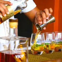 Barman nalewa cachacę do szklanek z lodem i miętą.