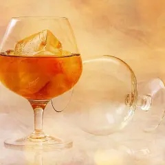Kieliszek brandy z lodem i pusty kieliszek na tle.
