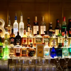 Rząd butelek alkoholi, w tym tequilla, na półce baru.