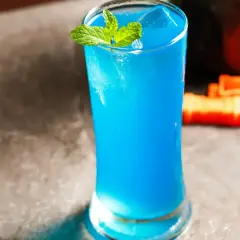 Błękitny drink z Blue Curaçao, lodem i miętą w szklance.