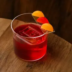 Czerwony koktajl Negroni z lodem i plasterkami pomarańczy na szkle.
