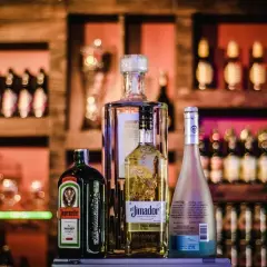 Butelka Jägermeister, Absolut, El Jimador i Hypnotiq. Różne rodzaje alkoholi na półce barowej.