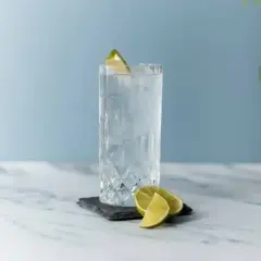 Szklanka z lodem i plasterkami limonki, ozdobiona limonką na brzegu.