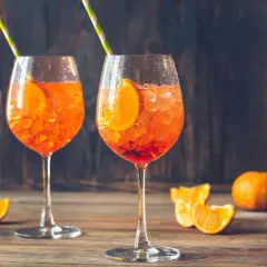 Dwa orzeźwiające drinki Aperol Spritz z plastrem pomarańczy i słomkami. Idealne na letnie popołudnie.