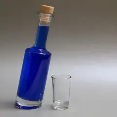 Niebieski likier w butelce z korkiem i pusty kieliszek.
