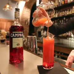 Barman nalewa czerwony koktajl z Campari do szklanki z lodem.