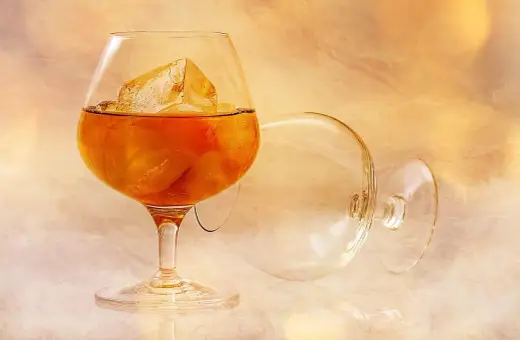 Kieliszek brandy z lodem i pusty kieliszek na tle.