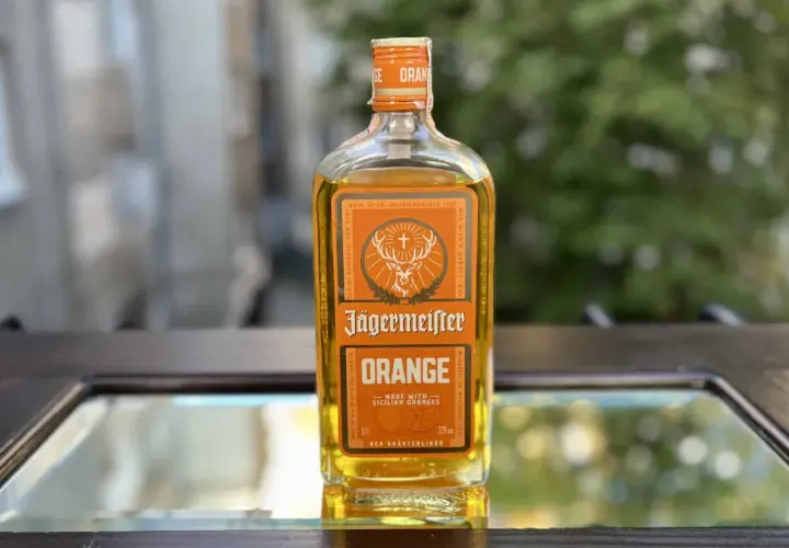 Butelka Jägermeister Orange na lustrzanym tle.