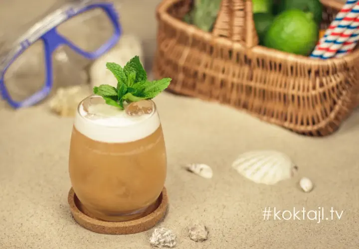 Orzeźwiający vodka sour z miętą na plaży, obok koszyka z limonkami i maski do nurkowania. Idealny na wakacje!