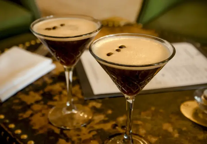 Dwa kieliszki Espresso Martini z gęstą pianką i ziarnami kawy na wierzchu.