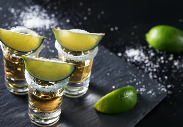 Trzy kieliszki tequili z solą i limonką, gotowe do degustacji. Oto jak pić tequilę, by poczuć jej smak.