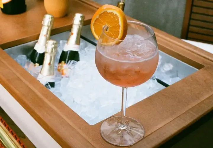 Orzeźwiający drink z pomarańczą i lodem, obok schłodzone butelki, idealne na aperitivo. Zastanawiasz się, jakie prosecco do Aperola?
