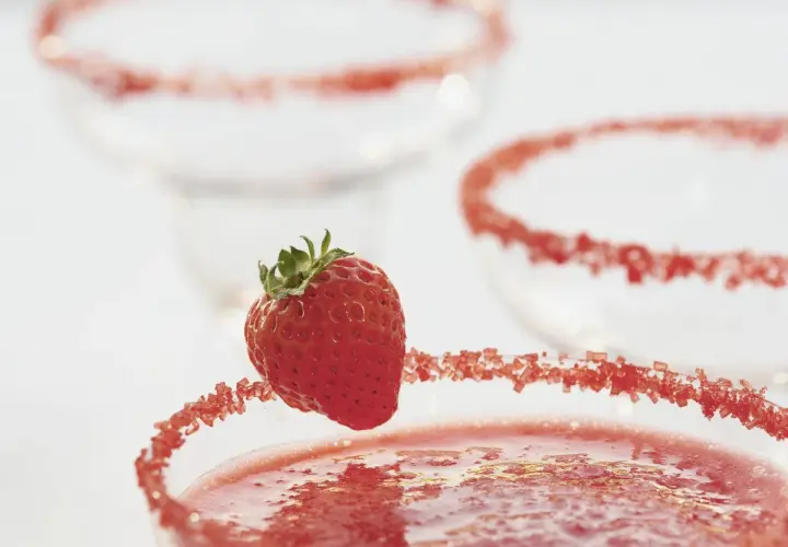 Truskawkowa margarita z ozdobnym brzegiem i świeżą truskawką.
