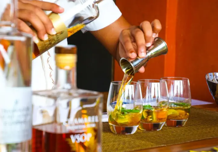 Barman nalewa cachacę do szklanek z lodem i miętą.