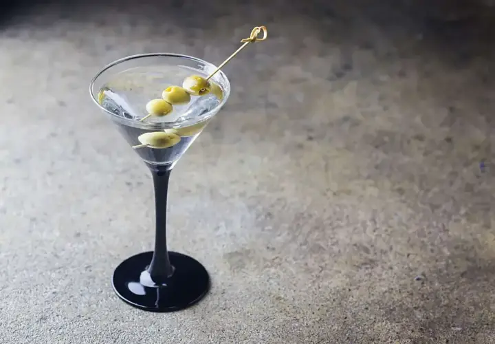Elegancki dirty martini z trzema oliwkami na wykałaczce, gotowy do degustacji.