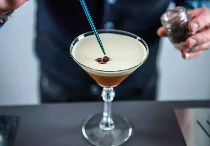 Barman dodaje ziarna kawy do drinka z pianką, przypominającego Espresso Martini. To właśnie kahlua co to za likier?
