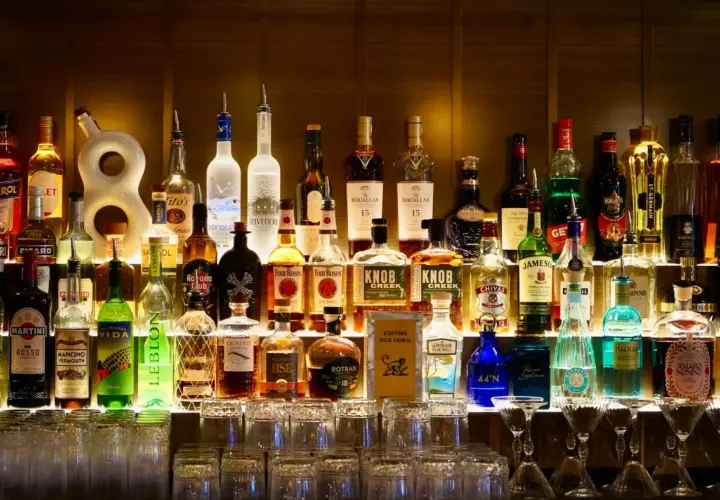 Rząd butelek alkoholi, w tym tequilla, na półce baru.