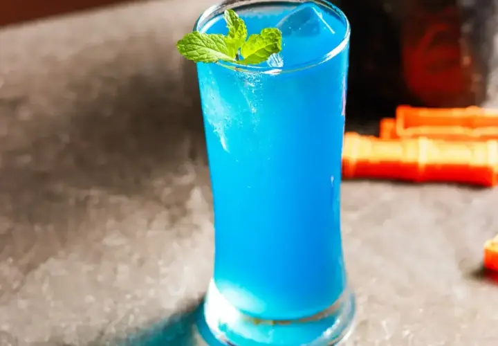 Błękitny drink z Blue Curaçao, lodem i miętą w szklance.