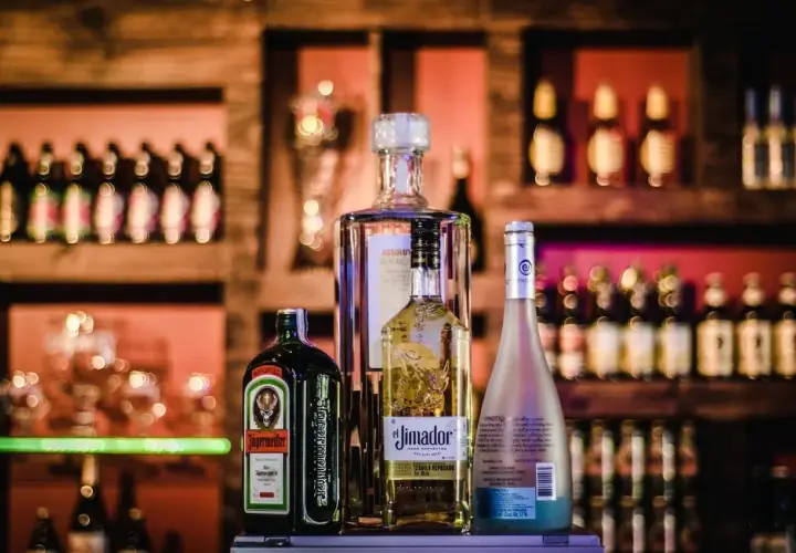 Butelka Jägermeister, Absolut, El Jimador i Hypnotiq. Różne rodzaje alkoholi na półce barowej.