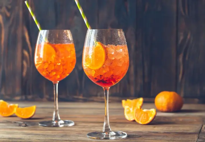 Dwa orzeźwiające drinki Aperol Spritz z plastrem pomarańczy i słomkami. Idealne na letnie popołudnie.