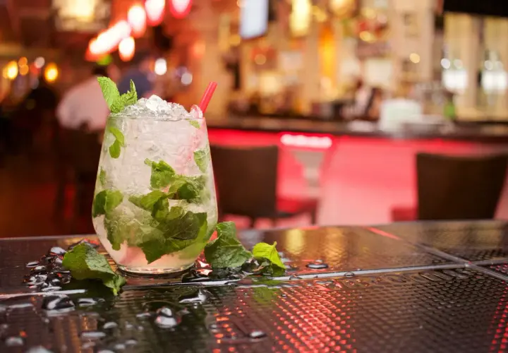 Szklanka orzeźwiającego mojito z miętą i lodem na barze.