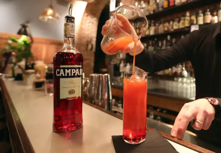 Barman nalewa czerwony koktajl z Campari do szklanki z lodem.
