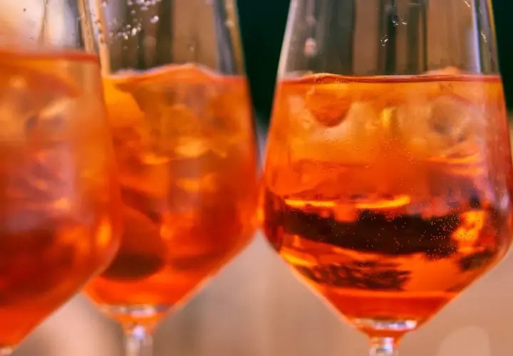 Orzeźwiający aperol bezalkoholowy z lodem w kieliszkach, idealny na letnie popołudnie.