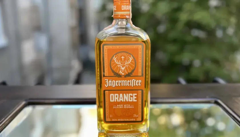 Butelka Jägermeister Orange na lustrzanym tle.