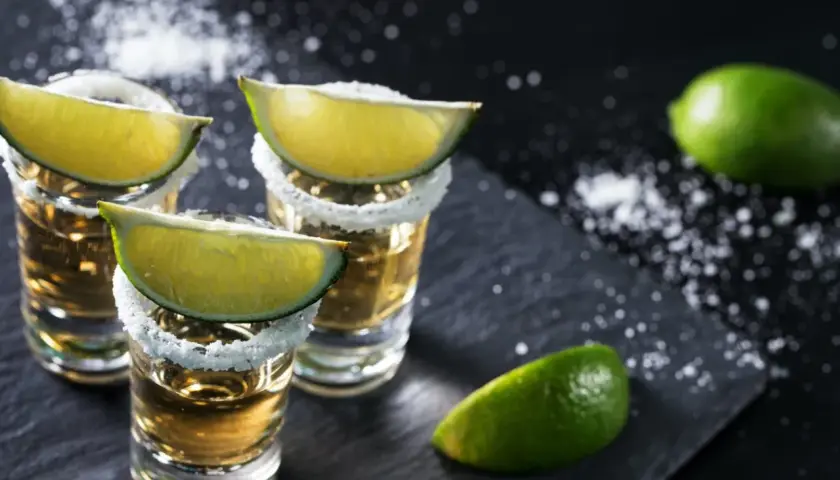 Trzy kieliszki tequili z solą i limonką, gotowe do degustacji. Oto jak pić tequilę, by poczuć jej smak.