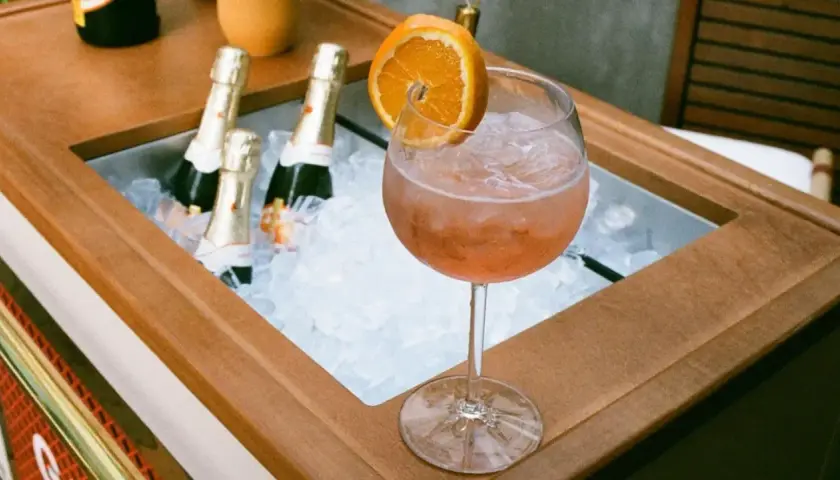 Orzeźwiający drink z pomarańczą i lodem, obok schłodzone butelki, idealne na aperitivo. Zastanawiasz się, jakie prosecco do Aperola?