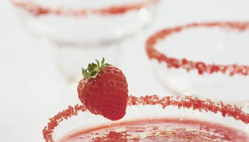 Truskawkowa margarita z ozdobnym brzegiem i świeżą truskawką.