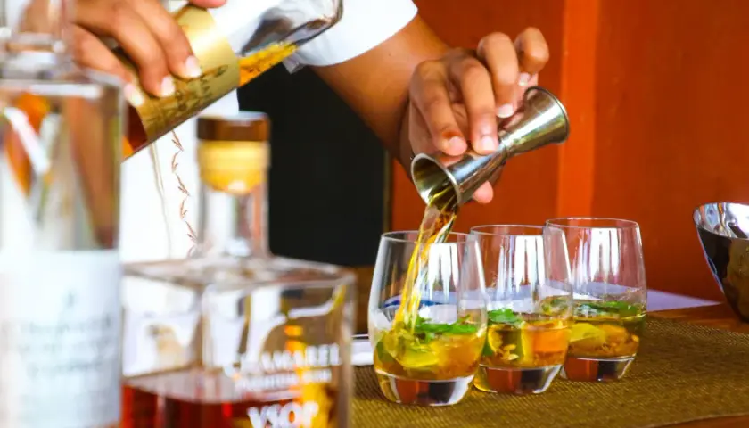 Barman nalewa cachacę do szklanek z lodem i miętą.