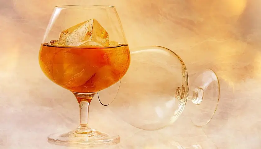 Kieliszek brandy z lodem i pusty kieliszek na tle.