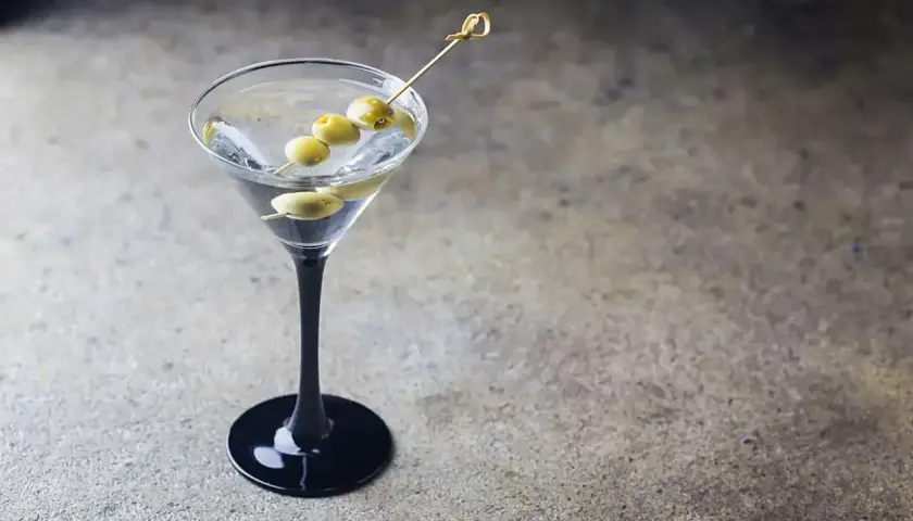 Elegancki dirty martini z trzema oliwkami na wykałaczce, gotowy do degustacji.