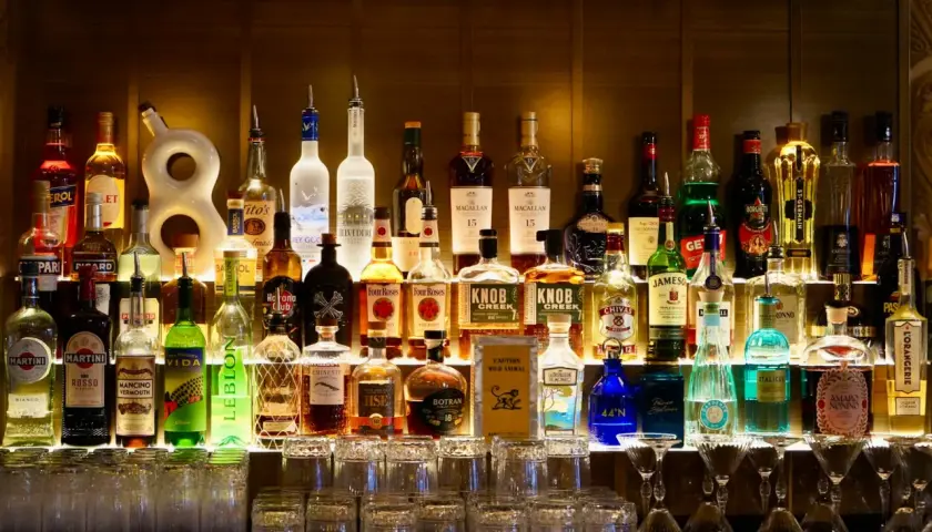 Rząd butelek alkoholi, w tym tequilla, na półce baru.