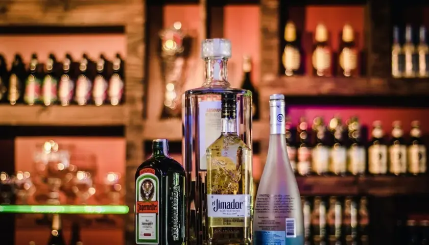 Butelka Jägermeister, Absolut, El Jimador i Hypnotiq. Różne rodzaje alkoholi na półce barowej.