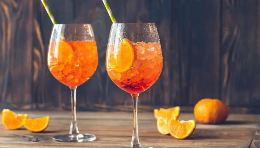 Dwa orzeźwiające drinki Aperol Spritz z plastrem pomarańczy i słomkami. Idealne na letnie popołudnie.