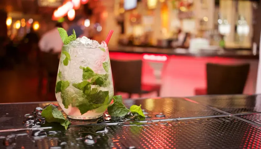 Szklanka orzeźwiającego mojito z miętą i lodem na barze.