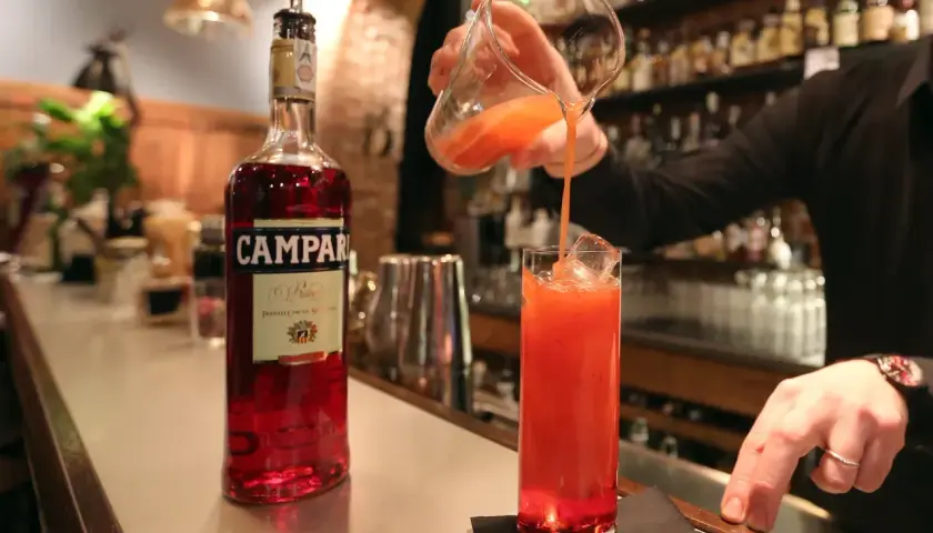 Barman nalewa czerwony koktajl z Campari do szklanki z lodem.