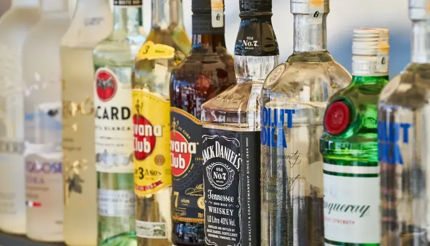 Różne rodzaje alkoholi: wódka, rum, whisky i gin. Widać butelki Bacardi, Havana Club, Jack Daniel's, Absolut i Tanqueray.
