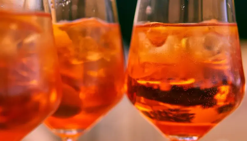 Orzeźwiający aperol bezalkoholowy z lodem w kieliszkach, idealny na letnie popołudnie.